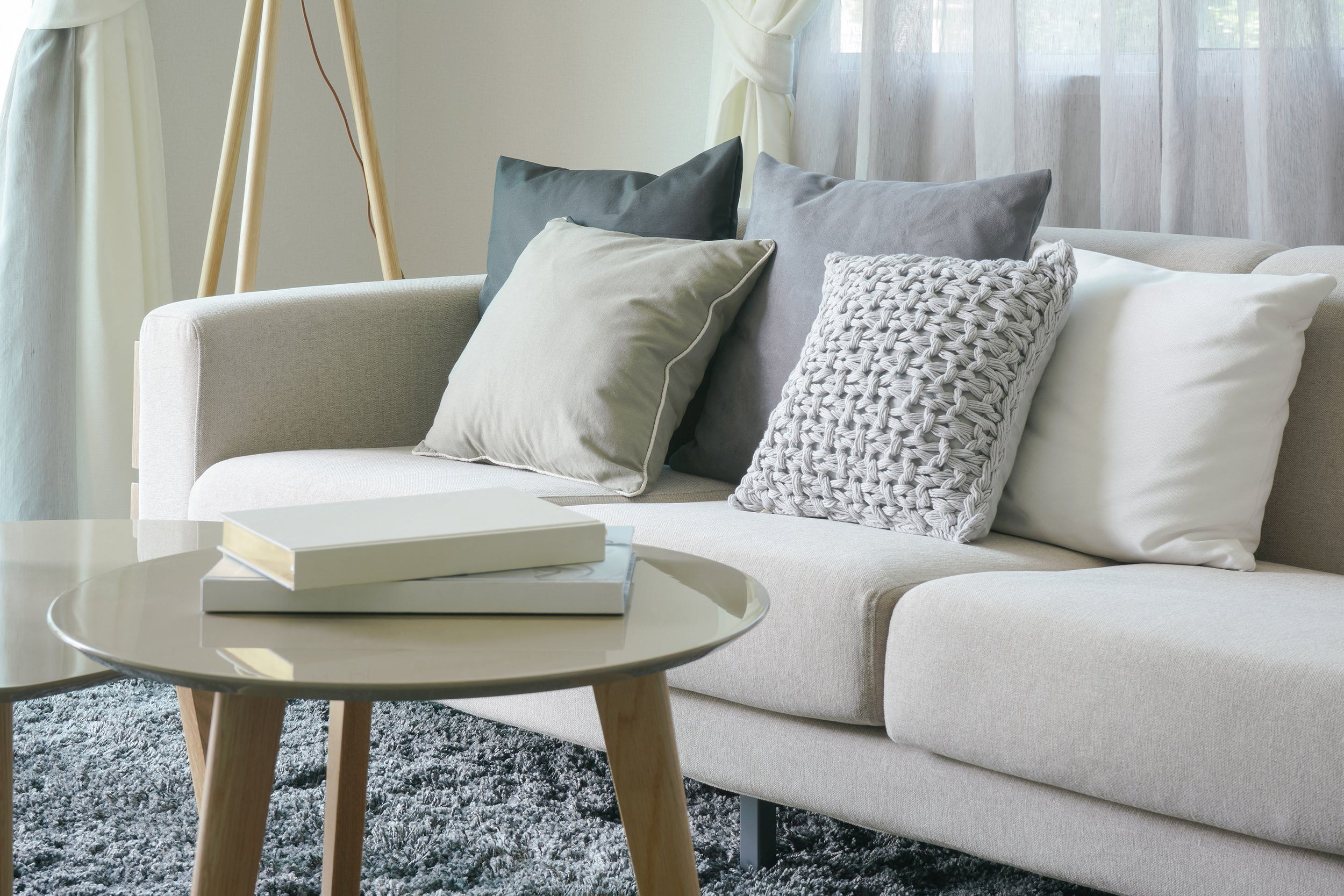 luxury apartment with white couch with grey pillows and a round coffee table